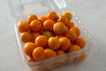 A view of a plastic container of orange colored gooseberries.