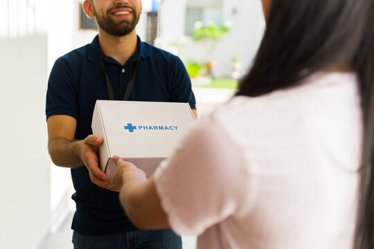 Closeup of a delivery man delivering medication in a white box with the word pharmacy on it to a woman