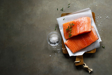Salmon. Fresh raw salmon fish fillet with cooking ingredients, herbs and lemon on dark background, top view