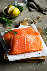 Salmon. Fresh raw salmon fish fillet with cooking ingredients, herbs and lemon on dark background,