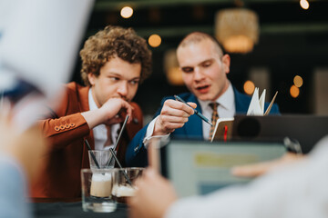 Two business professionals in discussion while collaborating on a project during a meeting at a cafe, with coffee and notepad.