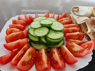 A plate of chopped tomatoes and cucumbers and a plate of pita bread with cheese. Preparing for a picnic in nature