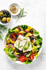 Fresh healthy vegetable Mediterranean food salad of Greek feta cheese, tomato, olives, pepper, lettuce and green basil leaves, top view