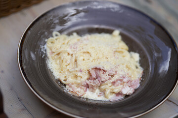 With bacon spaghetti Carbonara with bacon. Carbonara pasta in a ceramic plate on a gray countertop. Traditional Italian cuisine. Top view, close-up with the possibility of copying. High quality photo