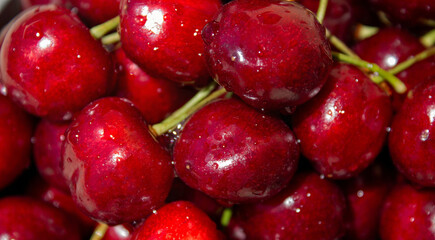 A bunch of red cherries are sitting on a table. The cherries are shiny and wet, and they are arranged in a pile