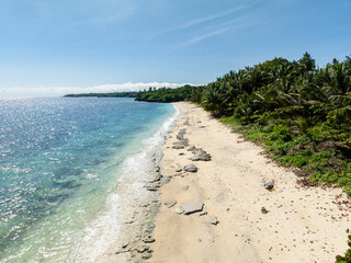 Sun reflection over the sea, waves crashing on rocks in sandy beach in Carabao Island. Romblon,...