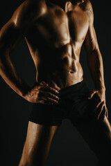 Fit man showing his abs and defined muscular body in a low light setting. Fitness and body building...