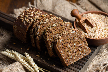 Dark rye bread with sunflower seeds cut into slices on a wooden background