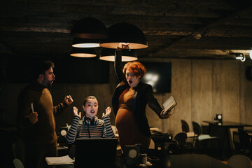 Young, business entrepreneurs celebrating at the office while working extra hours late at night....