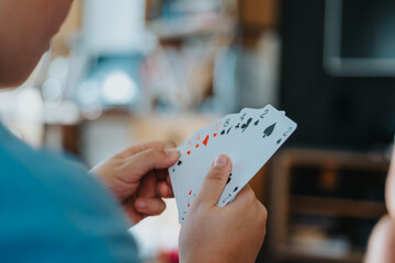 Close-up of a person holding playing cards in hand, enjoying a card game at home during leisure time.