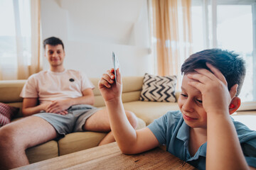 Family enjoying quality time at home playing card games on a relaxed day. Smiling boy and father bonding indoors.
