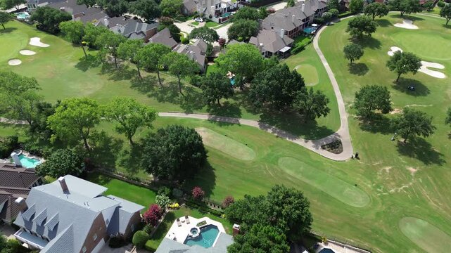 Club cars moving in curved path along upscale golf course community with luxury residential mansion houses concrete tiles roof, swimming pool East of Plano, Texas, Dallas Fort Worth metroplex