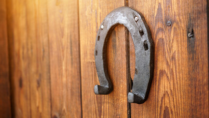 A horseshoe for good luck hanging on a wooden door. Symbol for luck and fortune. An iron lucky horseshoe - a talisman superstition for luck.