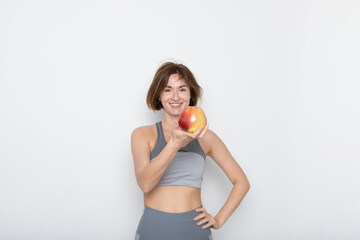 Close up portrait of pretty woman in sportswear holding apple isolated on white background. Healthy lifestyle concept