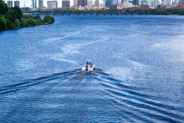 Small boat gliding through the serene Charles River waters, leaving a gentle wake, Boston,...