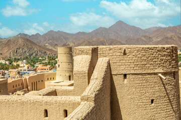 Bahla citadel fortress stone walls and round towers with mountains in the background, Bahla, Oman