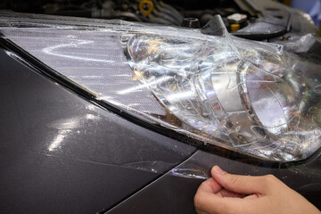 Protective film applied to car bumper in detailing workshop for safety and maintenance