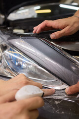 Protective film applied to car bumper in detailing workshop for safety and maintenance