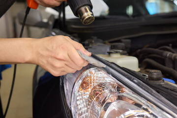 Protective film applied to car bumper in detailing workshop for safety and maintenance