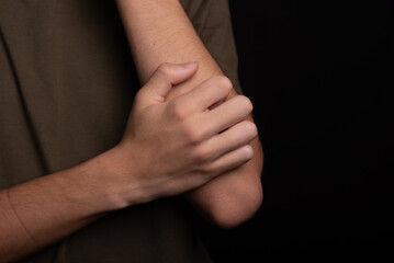 Young man scratching his arm with his hand. Skin disease. Irritation, allergy.