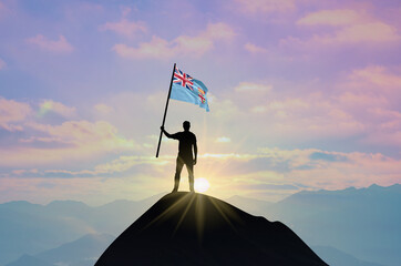 Waving flag of Fiji at the top of a mountain summit against sunset or sunrise. Fiji flag for Independence Day.