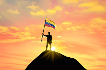 Waving flag of Colombia at the top of a mountain summit against sunset or sunrise. Colombia flag for Independence Day.