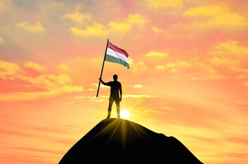 Waving flag of Hungary at the top of a mountain summit against sunset or sunrise. Hungary flag for Independence Day.