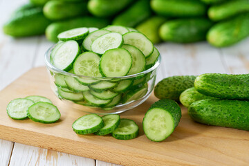 chopped cucumbers slices in a clear glass bowl on a wooden table, selective focus.