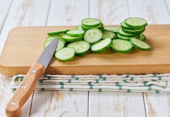chopped fresh cucumbers slices on a cutting board, on a light table, selective focus.