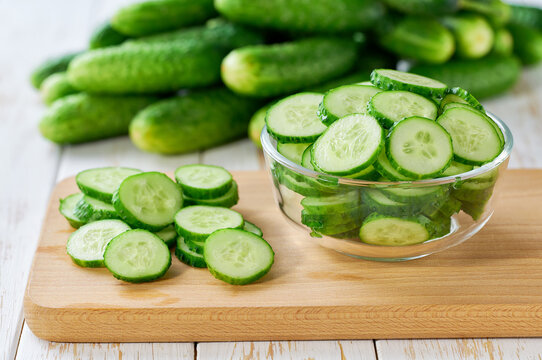 chopped fresh cucumbers slices in a clear glass bowl on a light table.
