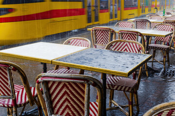 A train is passing by a restaurant with tables and chairs outside