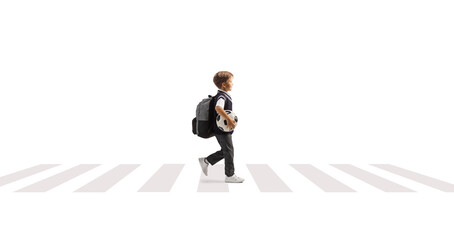 Full length profile shot of a schoolboy carrying a football and walking at a pedestrian crossing