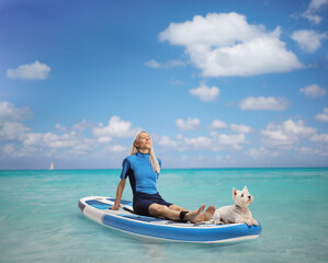 Woman with a dog pet sunbathing on a sup board