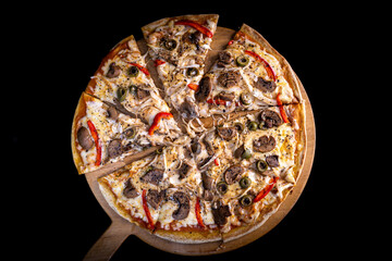 Close-up of a hand taking a slice of vegetarian pizza with onions, bell pepper, and vegetables on a wooden board.