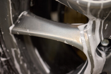 Detailed view of a car wheel rim being cleaned with foam for maintenance and shine