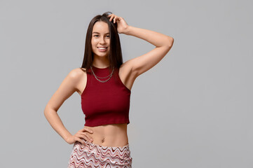 Beautiful young happy woman with piercing navel on grey background