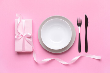 Festive table setting with present on pink background