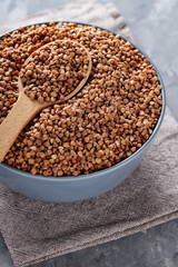 Buckwheat Grains in Wooden Spoon on Gray Background, Close Up