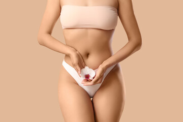 Young woman in underwear with beautiful orchid flower on brown background