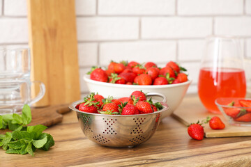 Bowl with tasty strawberries and juice on counter in kitchen