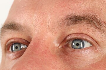 Man with beautiful blue eyes on white background, closeup