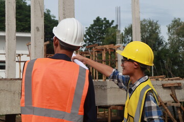 A team of engineers inspects beam work and installs concrete pillars according to the blueprint.