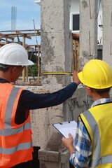 A team of engineers inspects beam work and installs concrete pillars according to the blueprint.