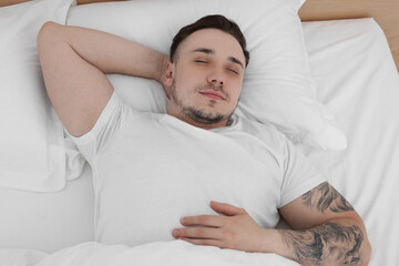 Bedtime. Handsome man sleeping in bed indoors, above view