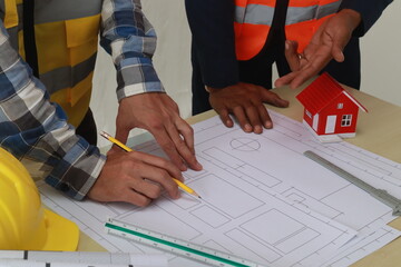 A team of engineers inspects beam work and installs concrete pillars according to the blueprint.