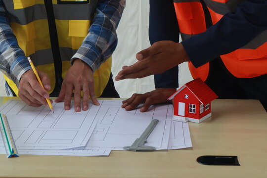 A team of engineers inspects beam work and installs concrete pillars according to the blueprint.