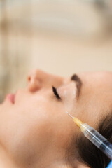 Cosmetology injections for getting rid of wrinkles. Young caucasian girl improves skin condition in...