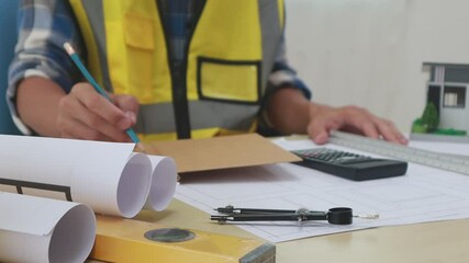 A male engineer inspects a structural model of a house at his workstation, ensuring compliance with design specifications and safety standards.