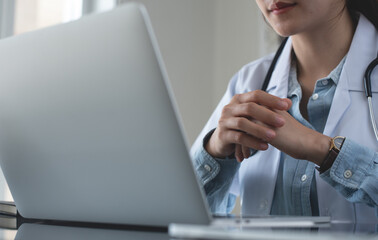 Telemedicine concept. Asian woman doctor listening to online patient on laptop computer sitting at...