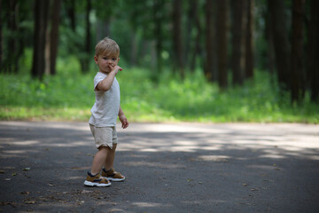 Fototapeta premium A young child walks along a path in a lush green park or forest. 